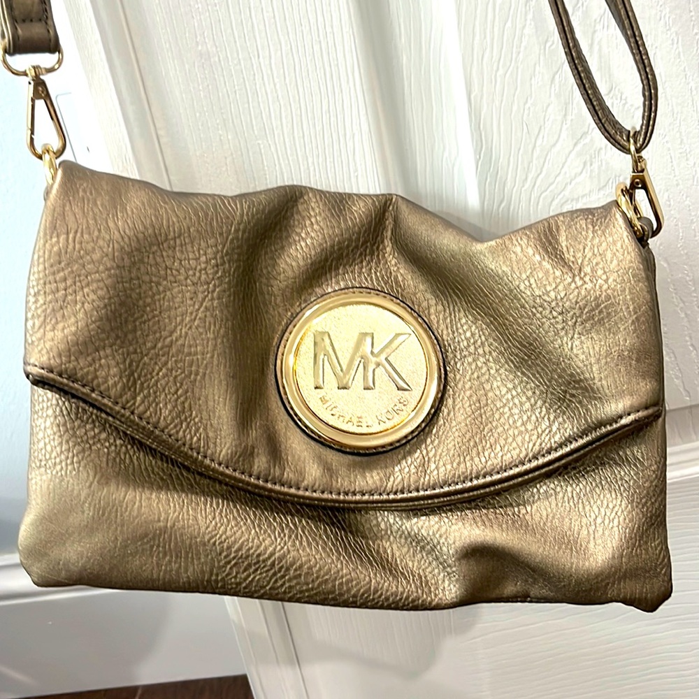 Womens bronze gold adjustable strap handbag with flap closure.